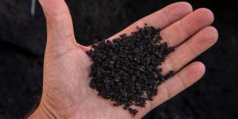 Handful of processed black rubber granules from ground scrap tires