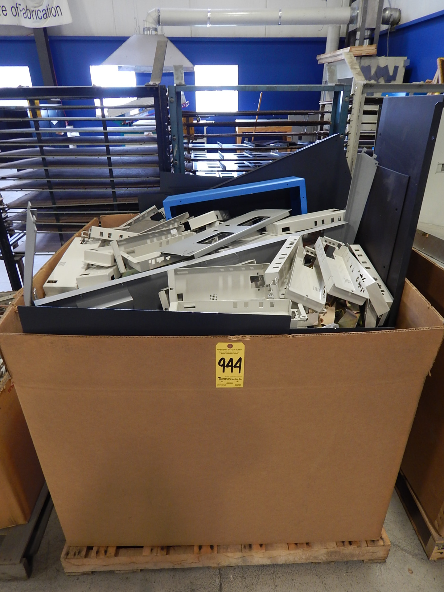 Scrap sheet metal parts collected in a large pallet-mounted cardboard box